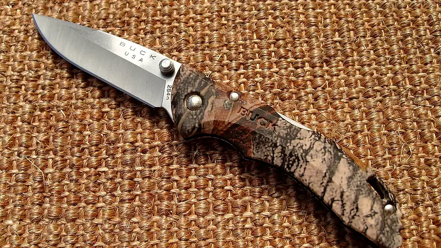 Buck Bantam folding knife with a camouflage handle on a woven mat