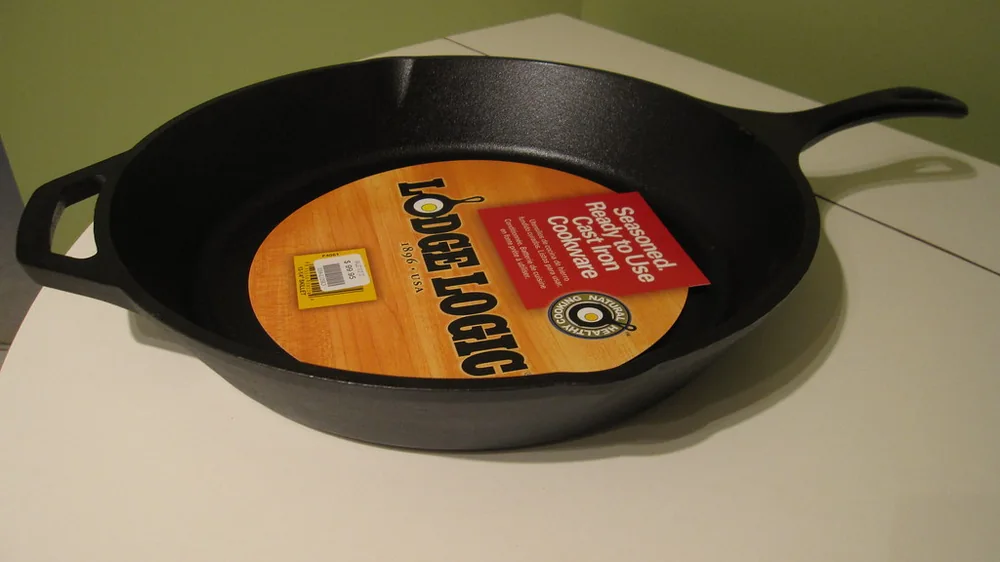 Black Lodge Logic cast iron skillet with the yellow and orange Lodge label on a kitchen counter