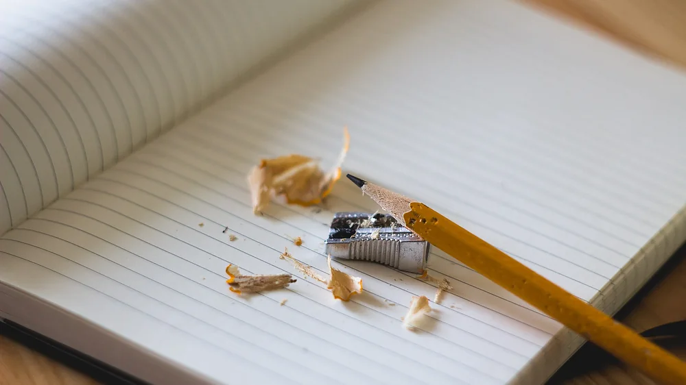A ruled paper notebook with a pencil and pencil shavings on the page. Representative photo, not the exact product.