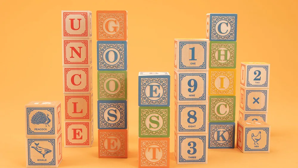 Uncle Goose Classic ABC Blocks stacked to spell UNCLE GOOSE, with numbers and animal blocks, on an orange background