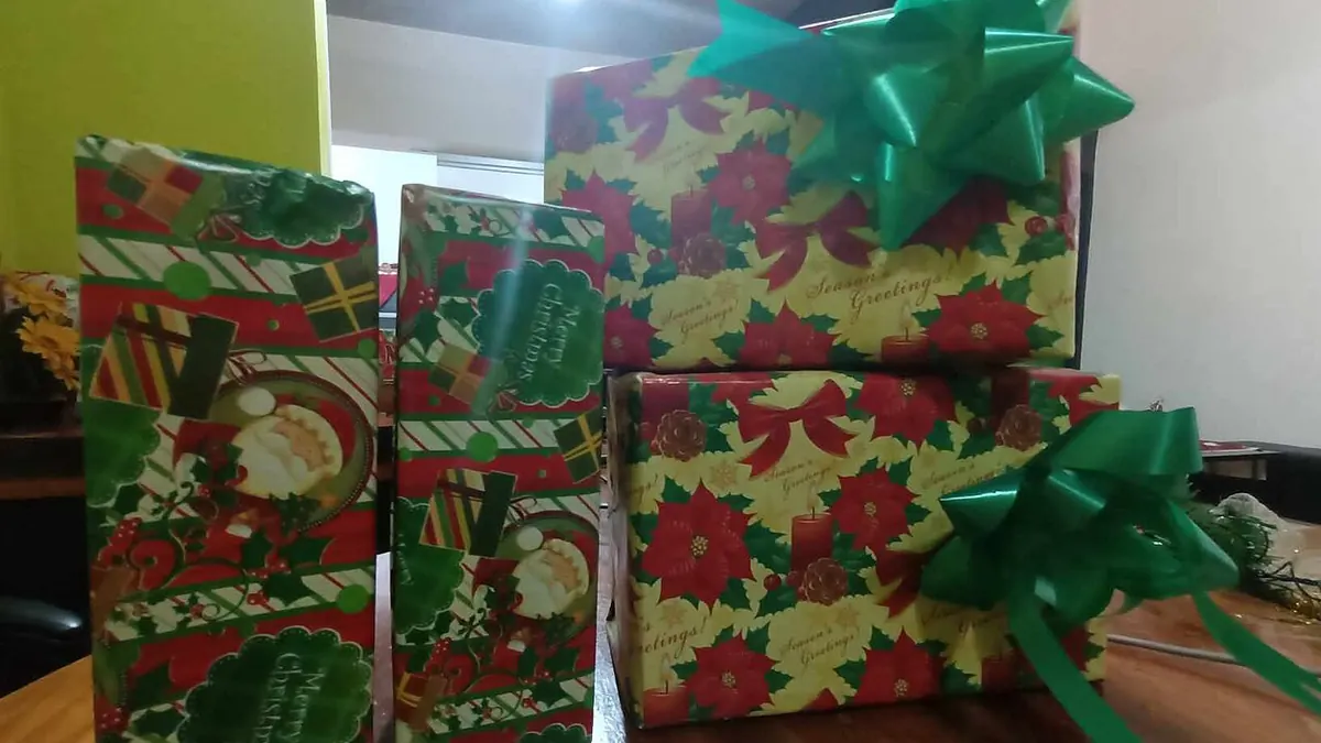 Wrapped holiday presents with green bows on a wooden floor